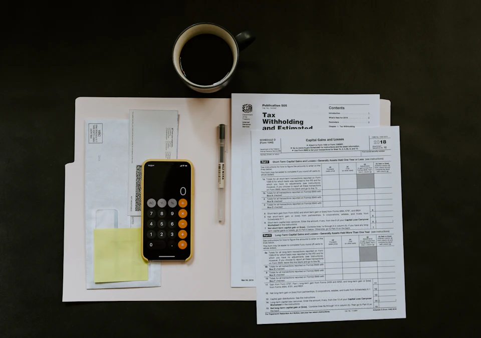 Black Android smartphone near ballpoint pen, tax withholding certificate on top of white folder