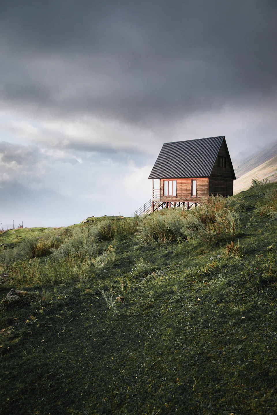 A small wooden cabin sits on a grassy hill