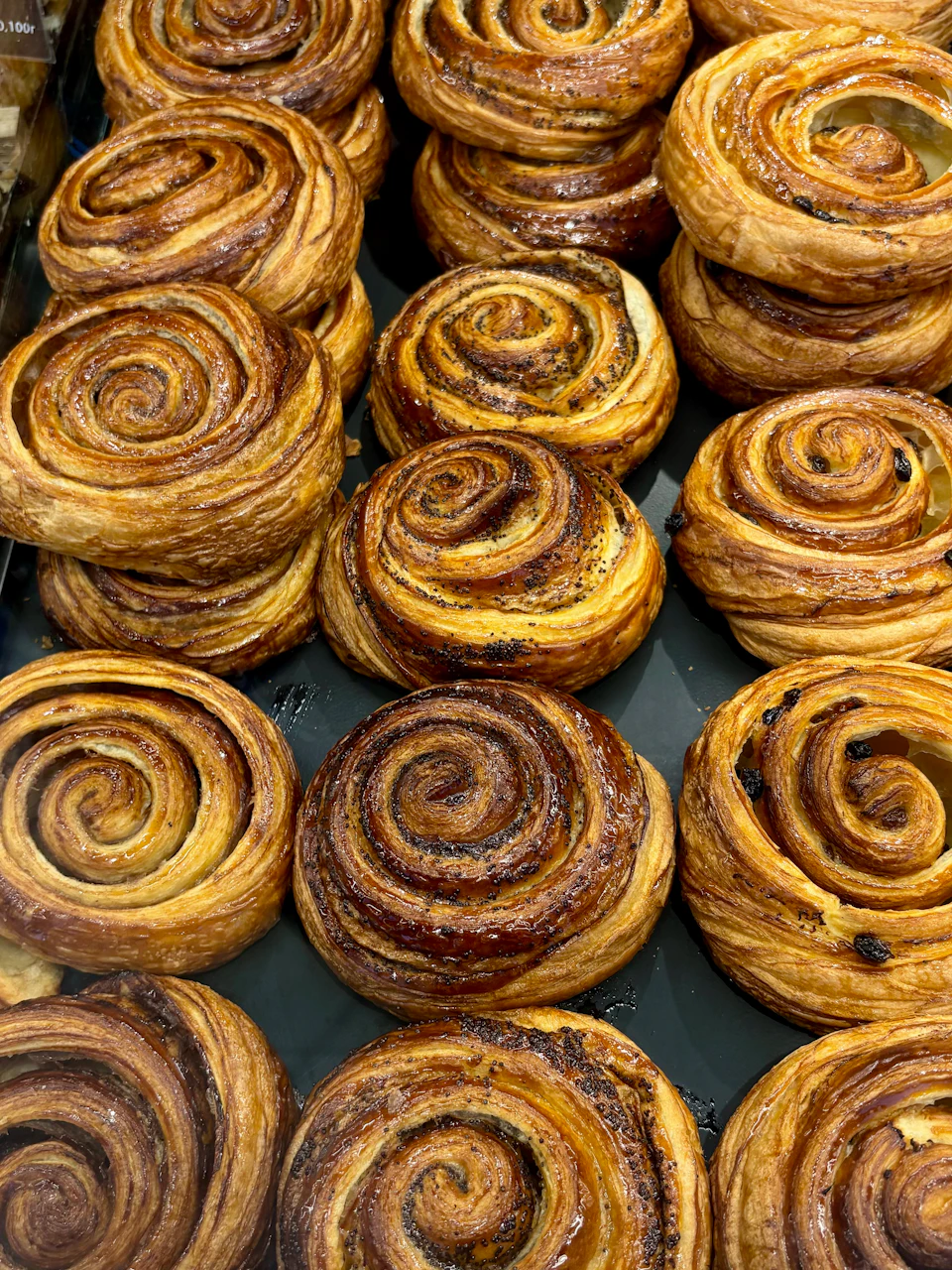 Many freshly baked cinnamon rolls displayed in a bakery